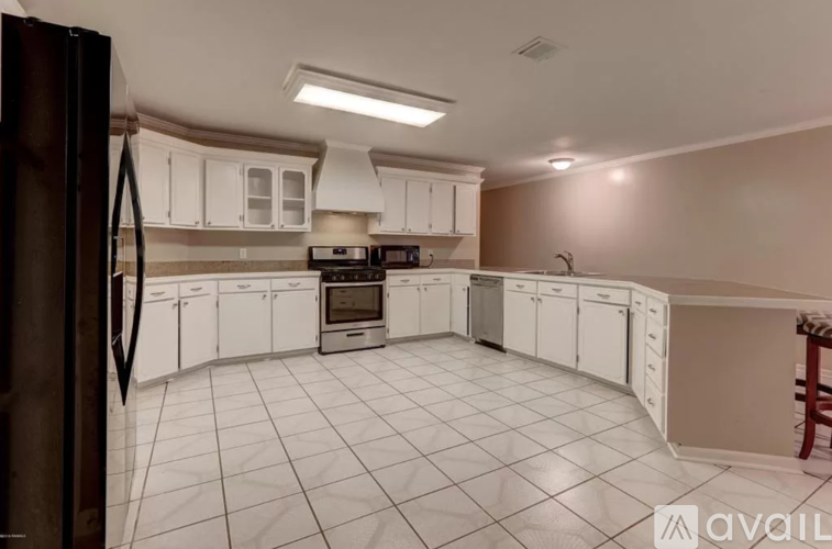 A kitchen with white cabinets and a black refrigerator.