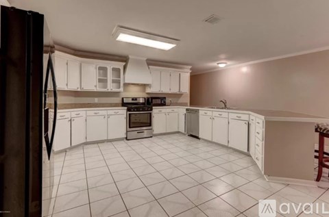 A kitchen with white cabinets and a black refrigerator.