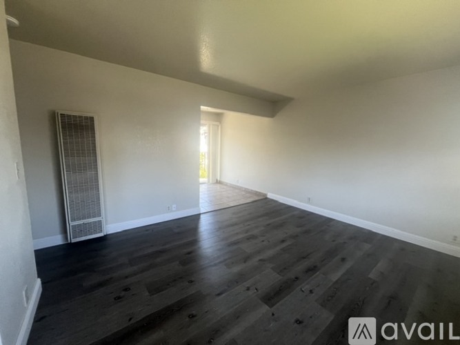 A room with wooden flooring and a window with blinds.