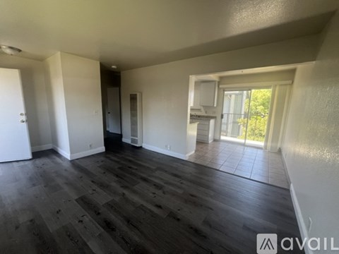 A spacious room with wooden flooring and white walls.