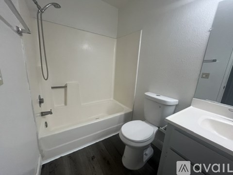 A white toilet sits next to a bathtub in a small bathroom.