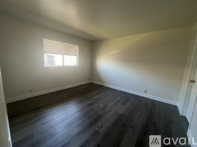 A room with wooden floors and a window letting in sunlight.