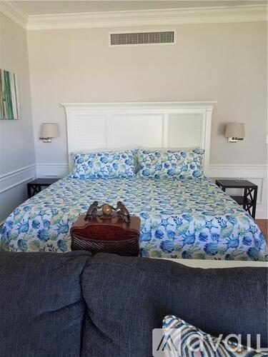 A bed with a blue floral comforter and a white headboard.