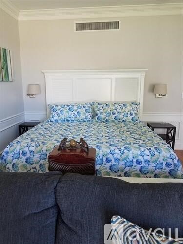 A bed with a blue floral comforter and a white headboard.