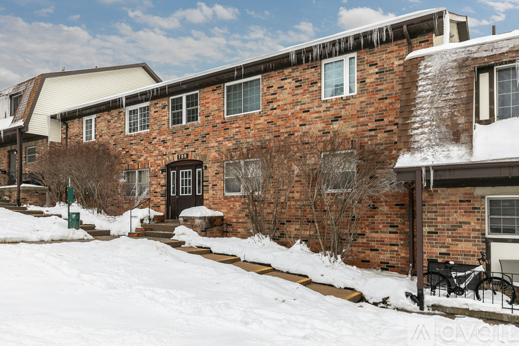 A red brick house with snow on the ground and a black door.