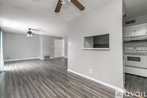 A spacious room with a ceiling fan and a kitchen area with stainless steel appliances.