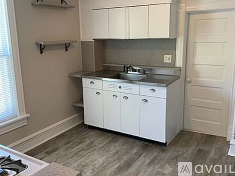 A kitchen with white cabinets and a stainless steel sink.