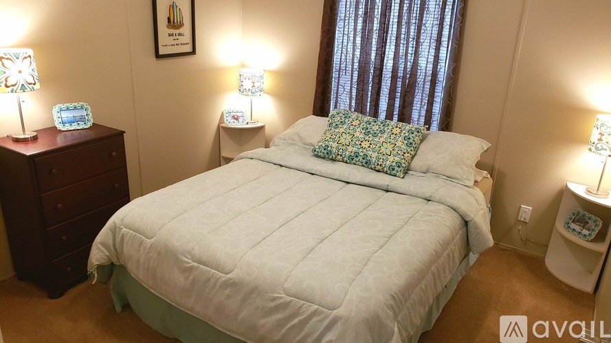 A bedroom with a large bed and two lamps on either side of the bed.