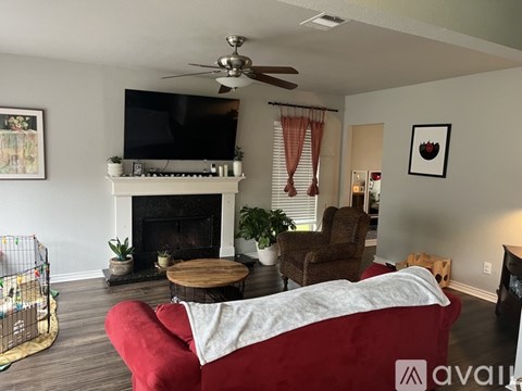 A living room with a red couch and a television on the wall.