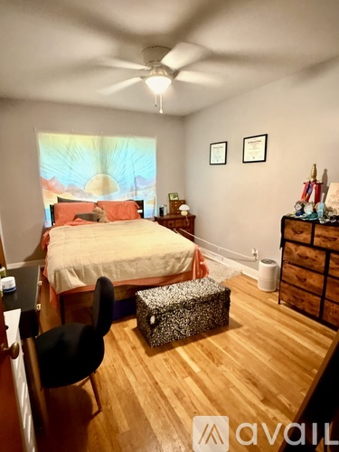 A bedroom with a bed, chair, and a ceiling fan.