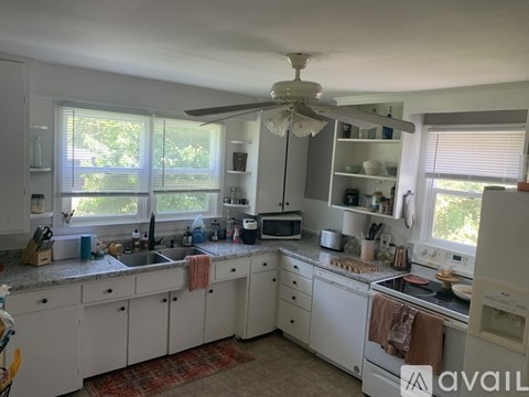 A kitchen with white cabinets and a red rug on the floor.