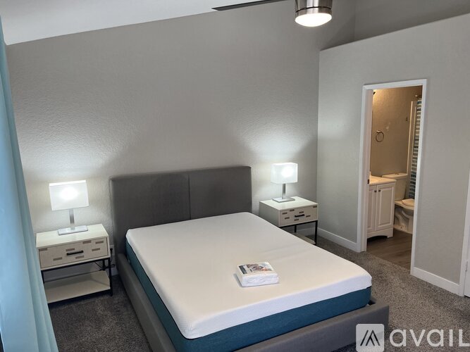 A bedroom with a bed, two nightstands with lamps, and a carpeted floor.