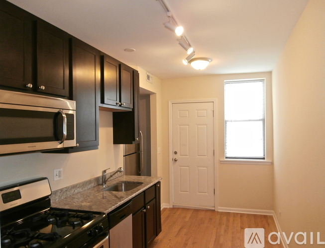 A kitchen with black cabinets and a white door.