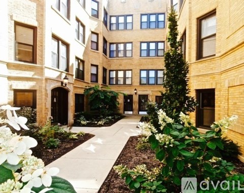 A courtyard surrounded by buildings with a white pathway and plants on the sides.