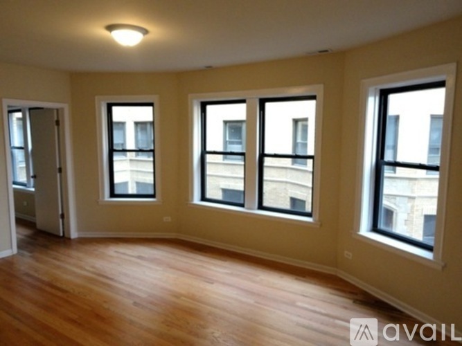 Three windows in a room with wooden floors and white walls.