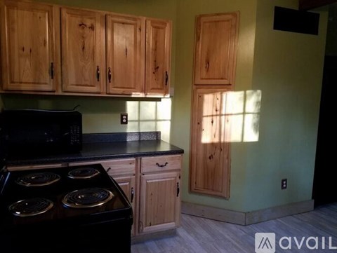 A kitchen with wooden cabinets and a black stove top oven.