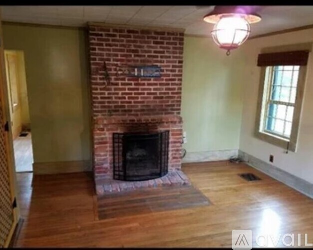 A room with a brick fireplace and wooden floors.