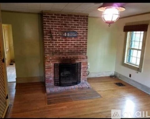 A room with a brick fireplace and wooden floors.