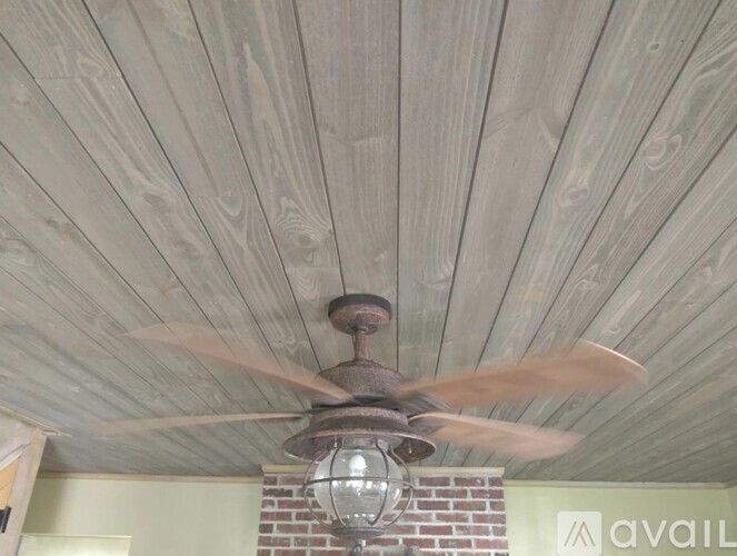 A ceiling fan with a light fixture hangs from a wooden ceiling.