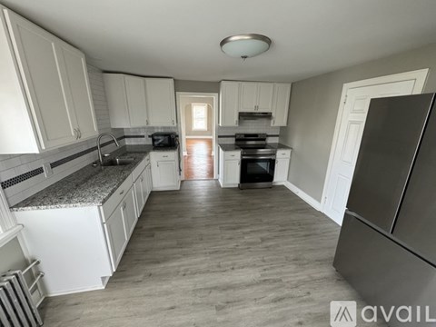 A kitchen with white cabinets and a grey refrigerator.