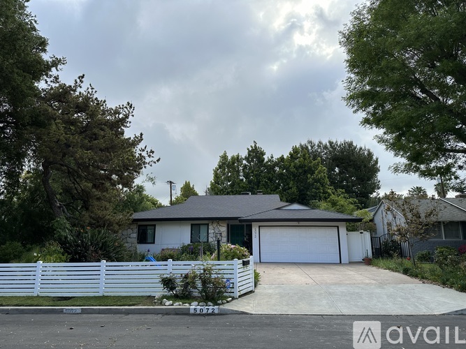 A house with a white fence and a garage is for sale.
