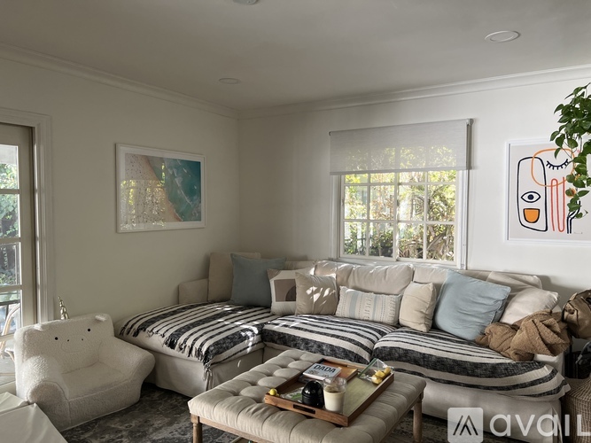A living room with a white sofa and a teddy bear.