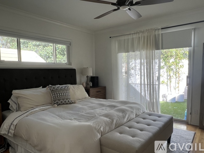 A bedroom with a large bed and a ceiling fan.