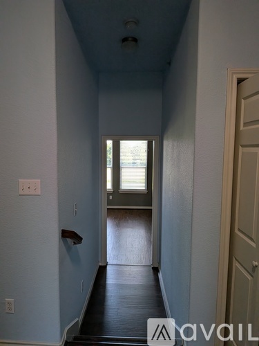 A hallway with a door on the right and a window in the distance.