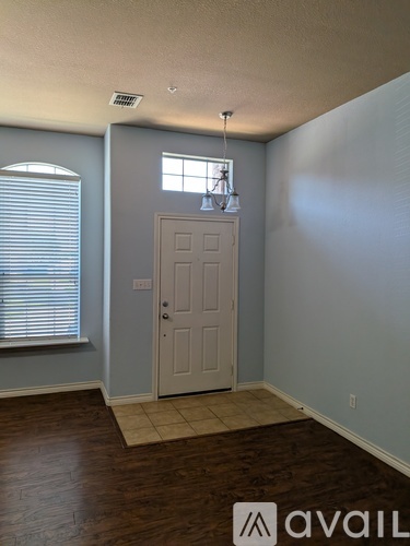 A room with a door, a window with blinds, and a light fixture on the ceiling.