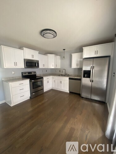 A kitchen with white cabinets and a wooden floor.