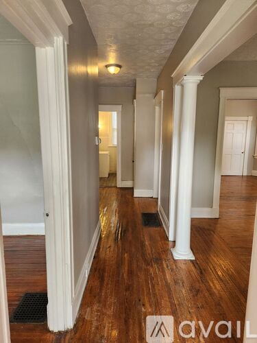 A long hallway with white columns and wood floors.