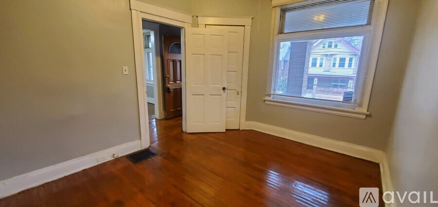 A room with a wooden floor and a window showing a building outside.