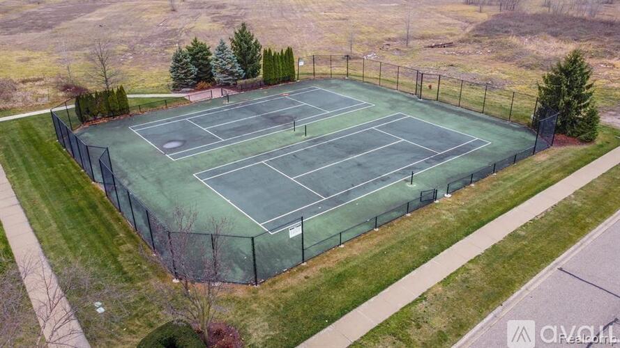 A tennis court surrounded by a fence and trees.