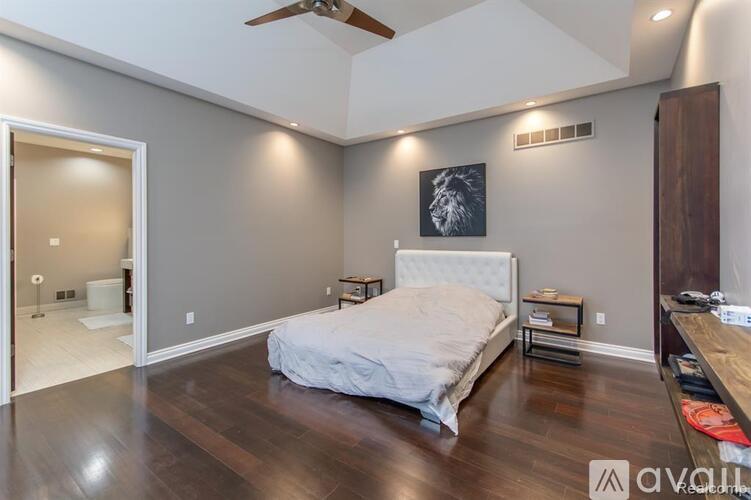 A bedroom with a bed, a ceiling fan, and a painting on the wall.