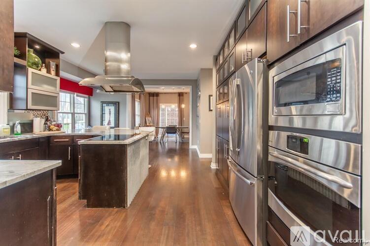 A modern kitchen with stainless steel appliances and wooden floors.