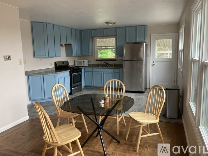 A kitchen with blue cabinets and a glass table with four chairs.