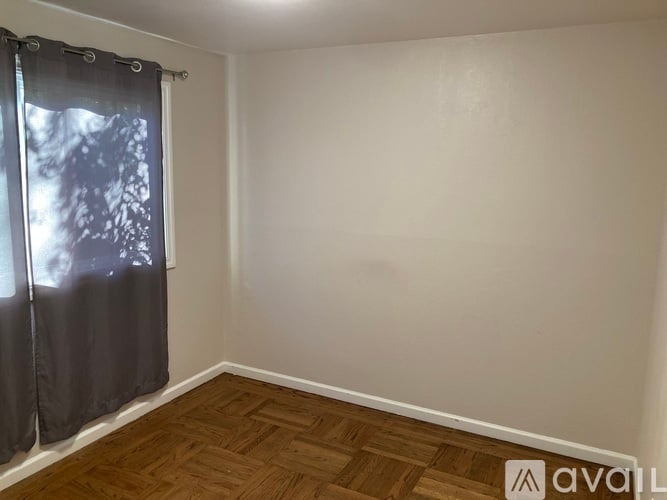 A room with wooden flooring and a window with curtains.