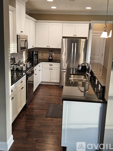 A kitchen with white cabinets and a black counter top.