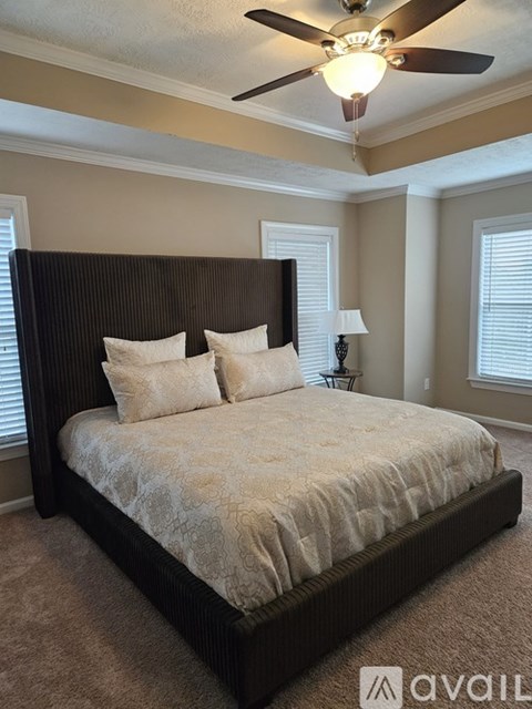 A bedroom with a large bed and a ceiling fan.