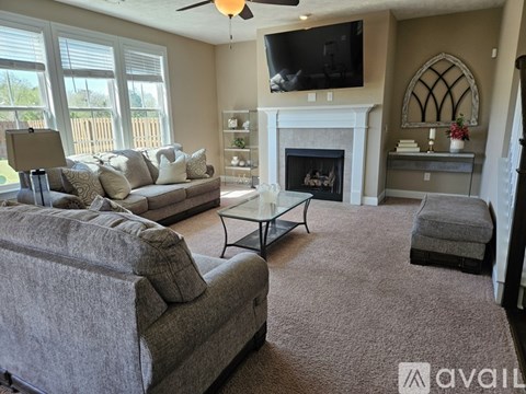 A living room with a grey couch and a fireplace.