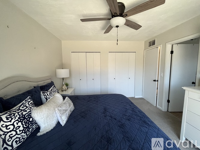 A bedroom with a bed, a ceiling fan, and a nightstand with a lamp.