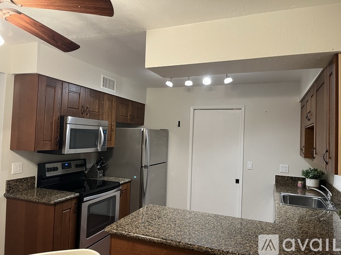 A kitchen with brown cabinets and a granite countertop.
