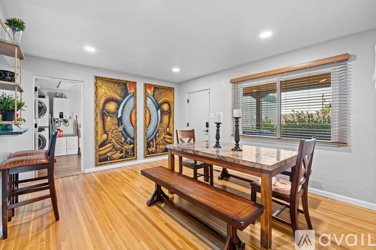 A dining room with a wooden table and bench, a painting on the wall, and a window with blinds.