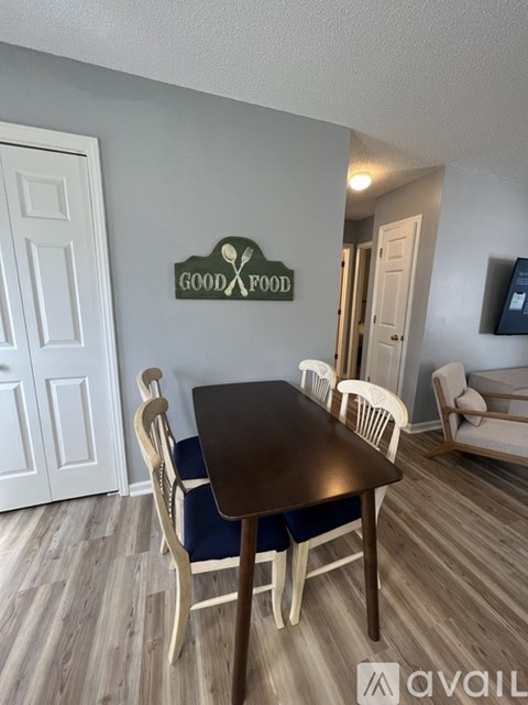 A dining room with a table and chairs and a sign on the wall.