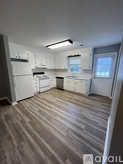 A kitchen with white appliances and wooden floors.