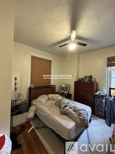 A bedroom with a bed, dresser, and ceiling fan.