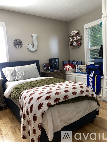 A bedroom with a bed covered in a blanket with red and brown spots on it.
