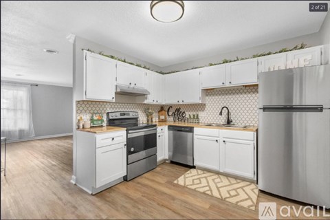 A kitchen with white cabinets and a wooden floor.