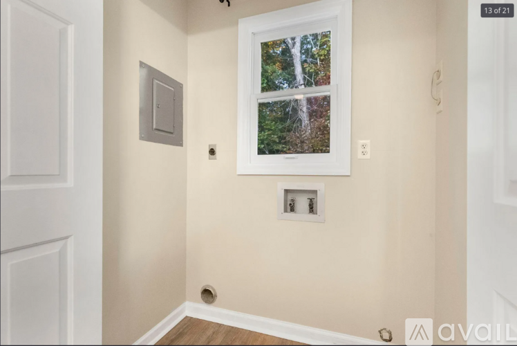 A room with a window showing trees outside and a light switch on the wall.