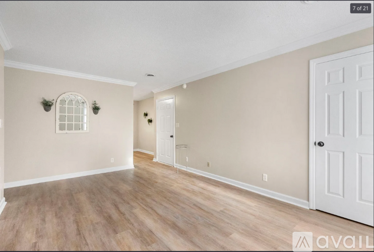 A spacious room with wooden flooring and a white door.